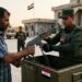 صورة تعبيرية تظهر يد تمسك سلاحًا ويد أخرى تضعها في صندوق يمثل الدولة، رمزًا لجهود حصر السلاح في العراق.